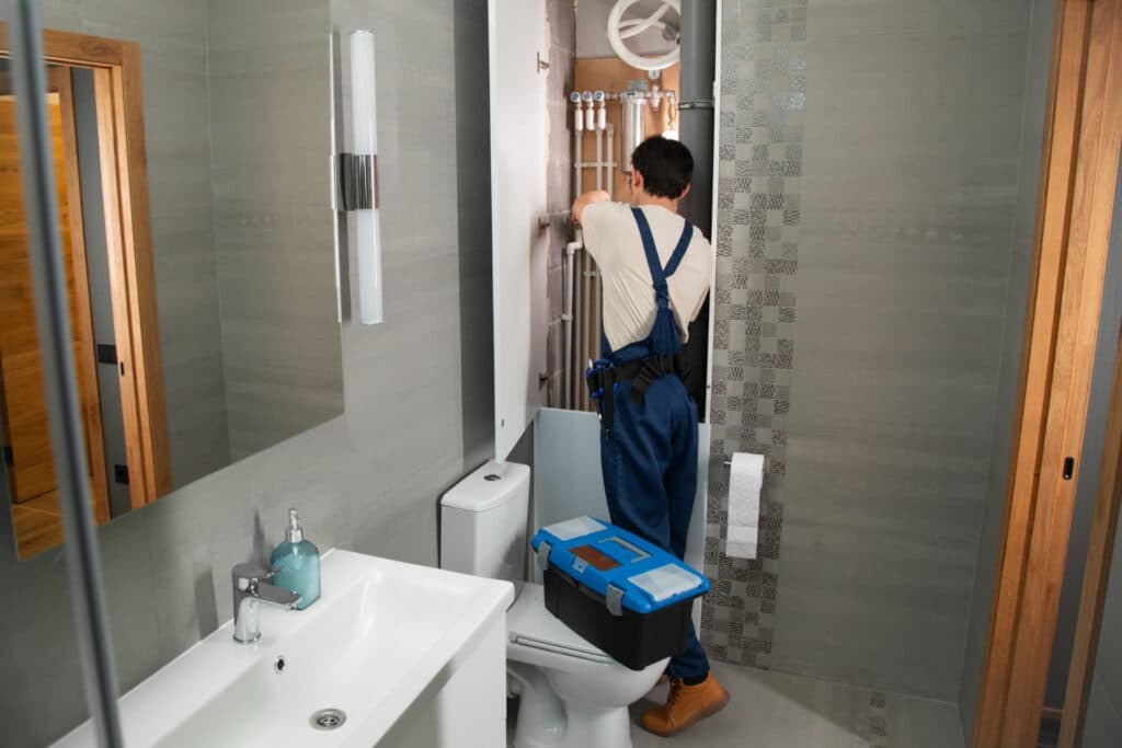 Plombier intervenant sur les canalisations d'une salle de bain