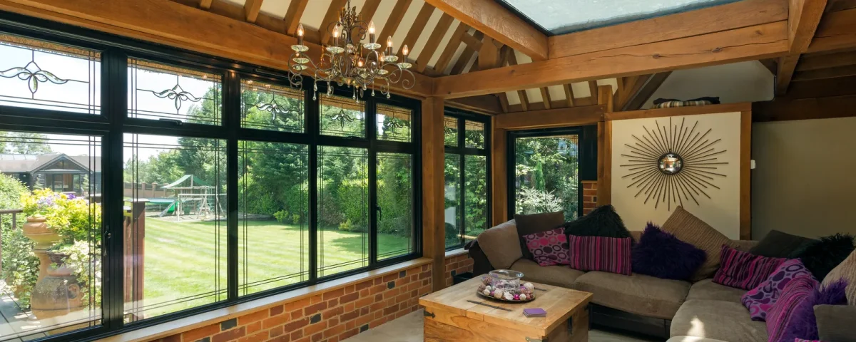 Extension de maison en véranda à charpente de chêne et toiture vitrée, ouverte sur le jardin